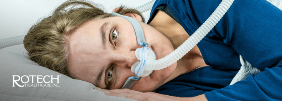 Woman lying on bed awake with CPAP nasal mask on face